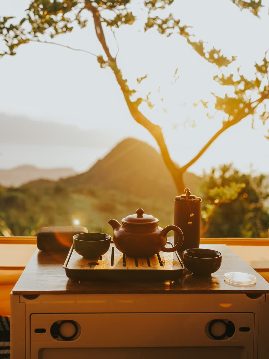 Ấm trà đặt trên bàn nhỏ, phía sau là núi lúc nắng chiều