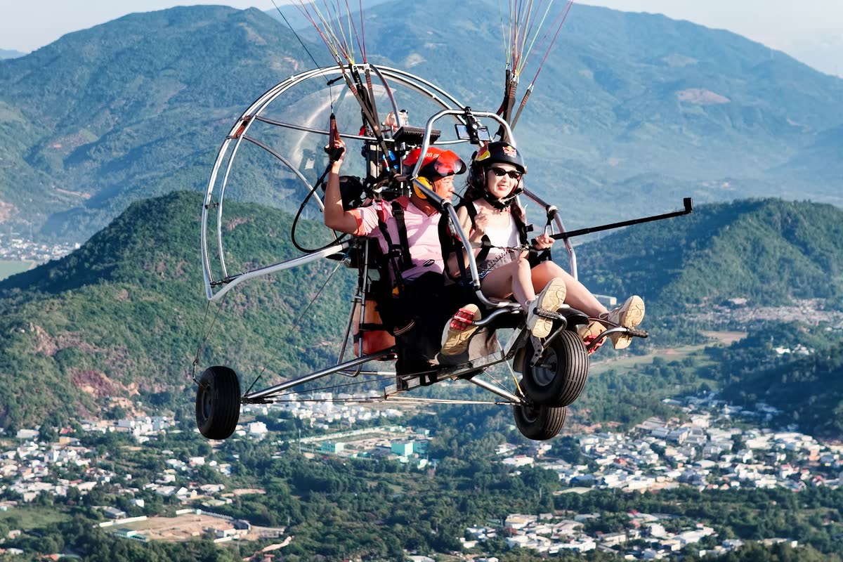 Hai người ngồi trên xe paramotor giữa trời.