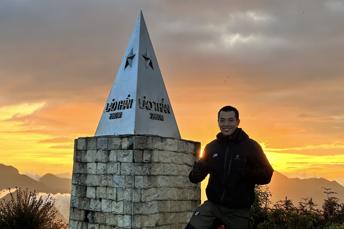 Bên cột mốc Lảo Thẩn, trời rực nắng phía sau.