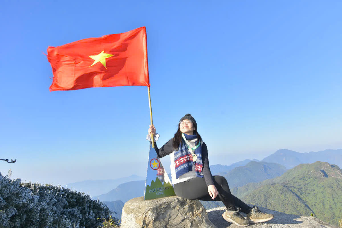 Cầm cờ đỏ sao vàng trên mỏm đá.