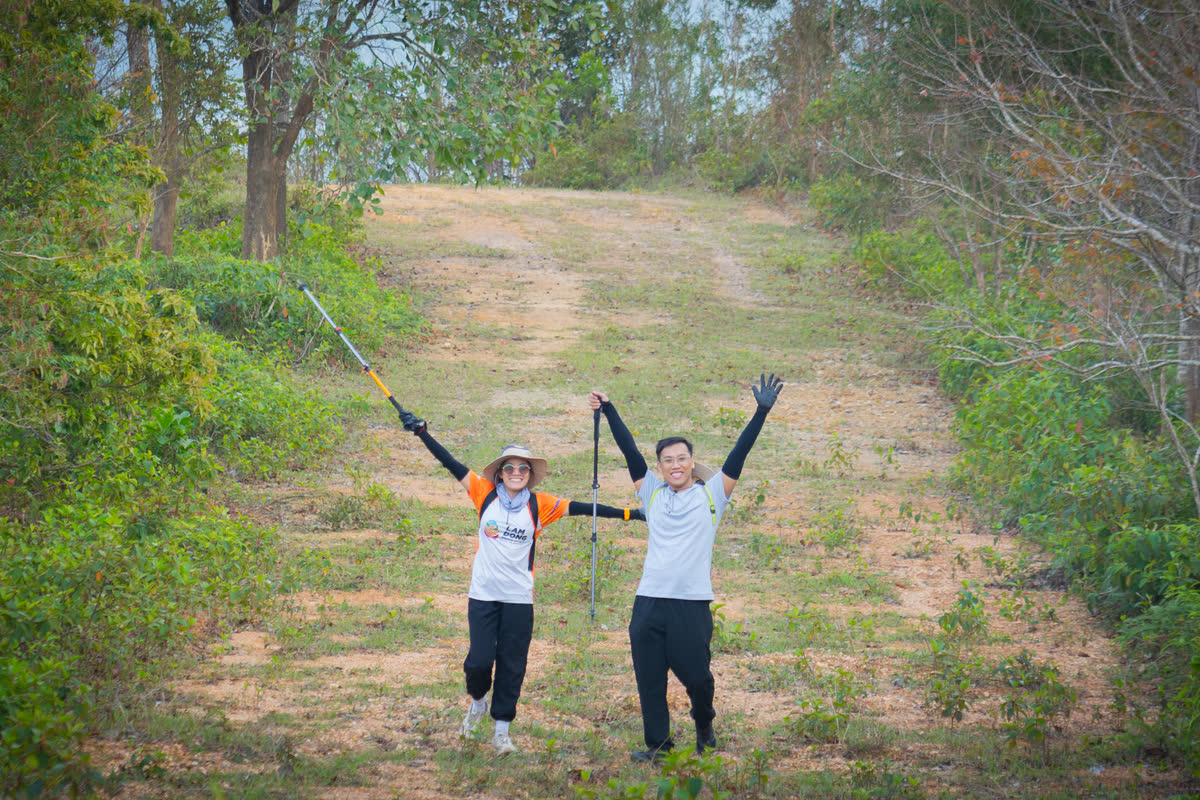 Hai người dang tay trên con đường mòn giữa rừng.