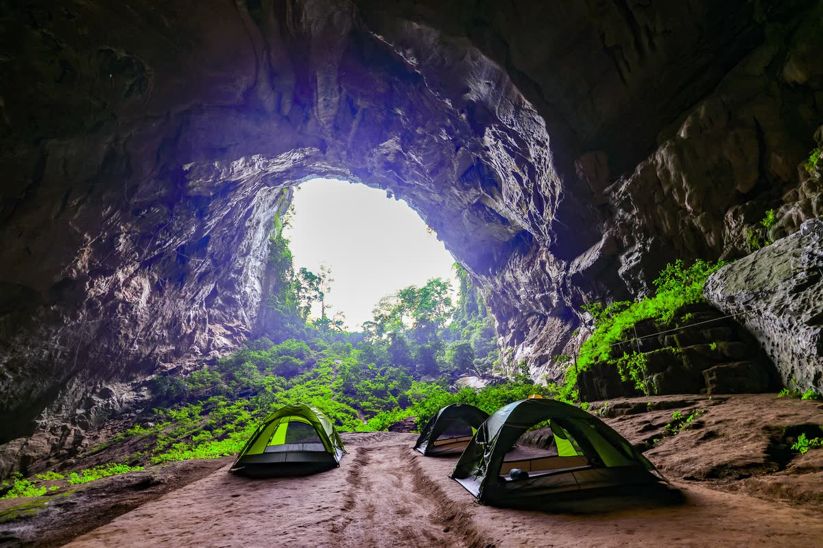 Lều dựng trong lòng hang, phía sau là cửa hang sáng.