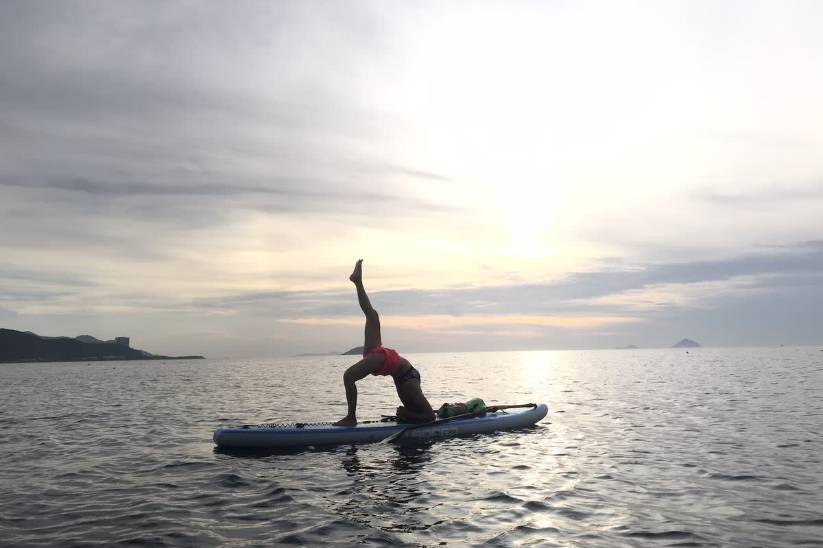 Tạo dáng yoga trên ván SUP giữa biển lặng.